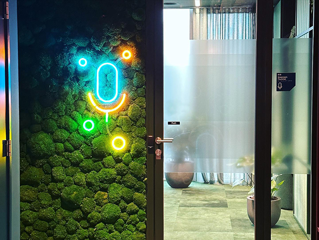 Google Neon Microphone Light Embedded In Green Plant Wall